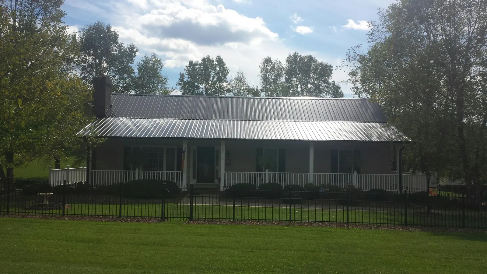 Gray metal roof on a brick ranch with a full width front porch — Gutter Guard Installation work by our crew in Brooks