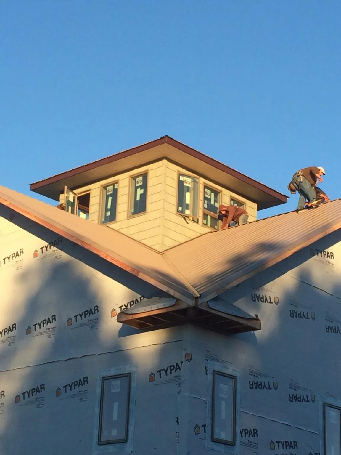 Roofers working around a rooftop cupola on a new metal roof at sunset — Roof Waterproofing in Brooks by Roofing Brothers